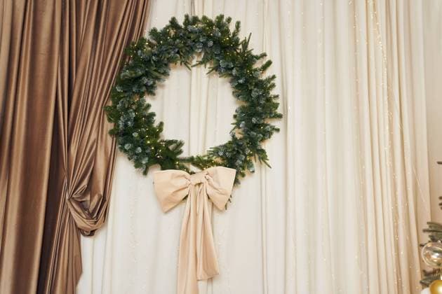 Christmas decor of a wreath with a bow, garland, string lights, brown and beige curtains. Background with copy space. It can be used as template, mock up for your art, decor, product Christmas decor of a wreath with a bow, garland, string lights, brown and beige curtains. Background with copy space. It can be used as template, mock up for your art, decor, product. Copyright: xZoonar.com DARYAxKOMAROVAx 22004048