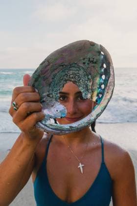 Creative Highlights Symbolfotos Woman wearing cross and holding opal shell in front of her face Laguna Beach, California, United States R_VCOZ240811-1508146-01 ,model released, Symbolfoto