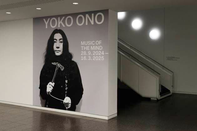 Einzelausstellung Music of the Mind von Yoko Ono in Düsseldorf. In der Eingangshalle der Kunstsammlung Nordrhein-Westfalen in Düsseldorf ist an der üblichen Wand grafisch der Hinweis auf Ausstellung und Dauer angebracht, in diesem Falle mit einem Porträt beziehungsweise frühen Foto von Yoko Ono. Im Übrigen bezeichnen K20 und K21 der Stiftung Kunstsammlung Nordrhein-Westfalen in Düsseldorf Kunst des 20. und des 21. Jahrhunderts. Bei Yoko Ono ist s beides. Düsseldorf Nordrhein-Westfalen Deutschland