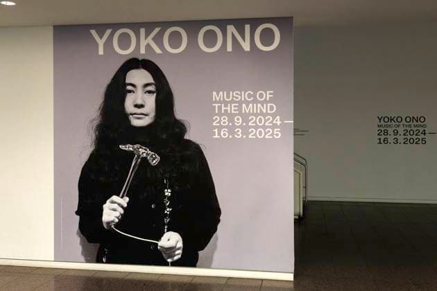 Einzelausstellung Music of the Mind von Yoko Ono in Düsseldorf. In der Eingangshalle der Kunstsammlung Nordrhein-Westfalen in Düsseldorf ist an der üblichen Wand grafisch der Hinweis auf Ausstellung und Dauer angebracht, in diesem Falle mit einem Porträt beziehungsweise frühen Foto von Yoko Ono. Im Übrigen bezeichnen K20 und K21 der Stiftung Kunstsammlung Nordrhein-Westfalen in Düsseldorf Kunst des 20. und des 21. Jahrhunderts. Bei Yoko Ono ist s beides. Düsseldorf Nordrhein-Westfalen Deutschland