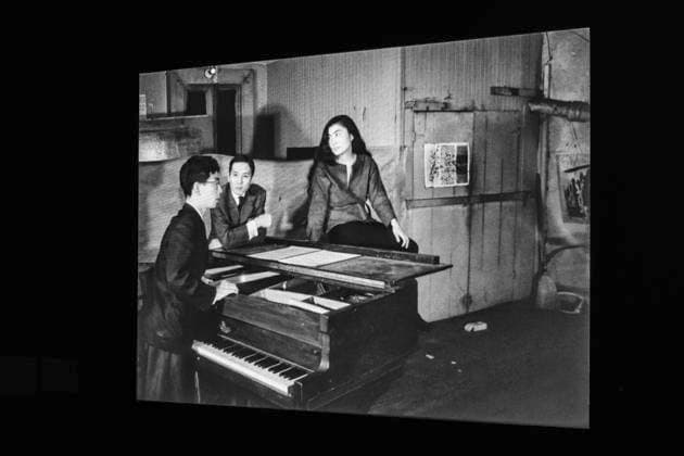 Einzelausstellung Music of the Mind von Yoko Ono in Düsseldorf. An die Wand projiziertes Schwarz-Weiß-Foto mit Yoko Ono auf dem Flügel sitzend. Das Foto enststand 1960 oder 1961 mit anderen Fotos zusammen mit Künstlerkolleginnen und Kollegen im Chambers Street Loft in New York. Das Foto stammt von dem japanischen Bildhauer Minoru Niizuma. Im Übrigen bezeichnen K20 und K21 der Stiftung Kunstsammlung Nordrhein-Westfalen in Düsseldorf Kunst des 20. und des 21. Jahrhunderts. Bei Yoko Ono ist s beides. Düsseldorf Nordrhein-Westfalen Deutschland