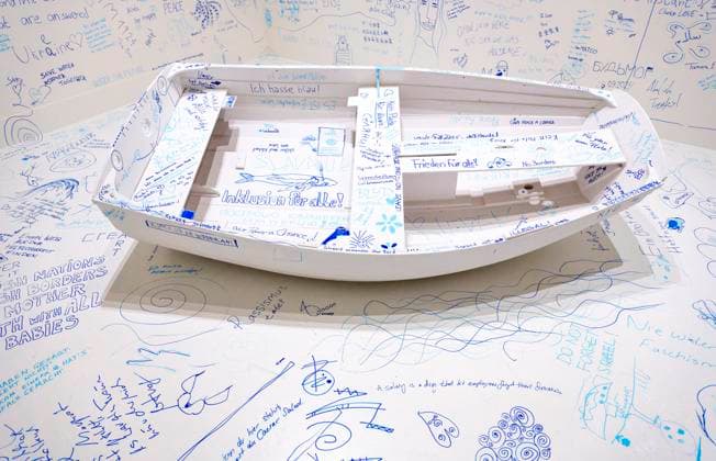 Einzelausstellung Music of the Mind von Yoko Ono in Düsseldorf. Add Colour - Refugee Boat ( Füge Farbe hinzu - Füchtlingsboot ), ein Holzboot, weiß angestrichen, wie auch der gesamte Raum weiß angestrichen ist. Es wird darauf hingewiesen, dass in diesem Raum zu Aufzeichnungszwecken gefilmt wird. Jeder Besucher kann irgendetwas Sinnhaftes oder auch Sinnloses mit Filzstift vermerken. Im Übrigen bezeichnen K20 und K21 der Stiftung Kunstsammlung Nordrhein-Westfalen in Düsseldorf Kunst des 20. und des 21. Jahrhunderts. Bei Yoko Ono ist s beides. Düsseldorf Nordrhein-Westfalen Deutschland