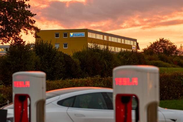 Ellwangen, Baden-Württemberg, Germany - October 1, 2024: Tesla Supercharger station in the foreground and the Varta building in Ellwangen in the background, illuminated by the sunset. Modern e-mobility and battery technology meet *** Tesla Supercharger-Station im Vordergrund und das Varta-Gebäude in Ellwangen im Hintergrund, beleuchtet vom Sonnenuntergang. Moderne E-Mobilität und Batterietechnologie treffen aufeinander