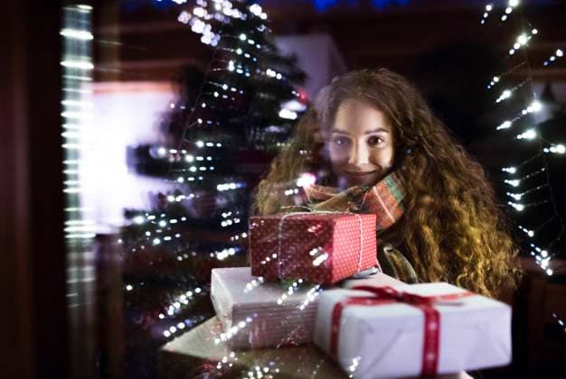 Student is coming home from university for the Christmas holidays, carrying bunch of Christmas presents and looking inside through window. Student is coming home from university for the Christmas holidays, carrying a bunch of Christmas presents and looking inside through the window. model released