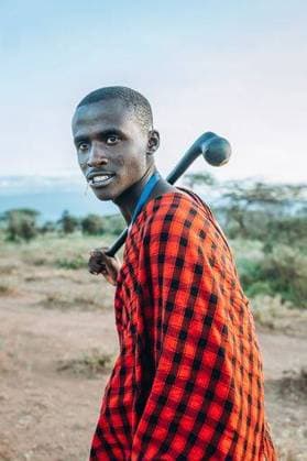 Creative Highlights Symbolfotos A young Maasai man in traditional attire with a stick over his shoulder in the savannah landscape 25588327 ,model released, Symbolfoto RECORD DATE NOT STATED
