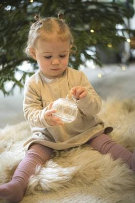 Ein Kleinkind hält eine glitzernde Weihnachtskugel vor einem Weihnachtsbaum in einer gemütlichen, winterlichen Atmosphäre A toddler holds a glittering Christmas bauble in front of a Christmas tree in a cosy, wintry atmosphere Copyright: imageBROKER ThomasxBaur ibxtba11521568.jpg ,model released, Symbolfoto ,property released