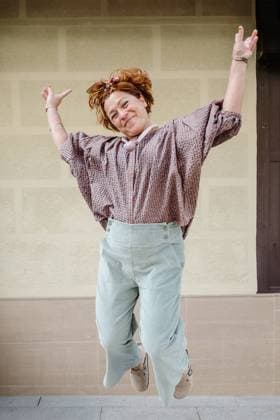 Creative Highlights Symbolfotos A euphoric woman celebrates with a joyful jump, arms flung wide and a bright smile Dressed casually in a patterned blouse and pastel pants, she exudes positive energy and carefree vitality against a plain wall background Model Released HodeiUnzueta_ID24122_698708_021 Copyright: xHodeixUnzuetax