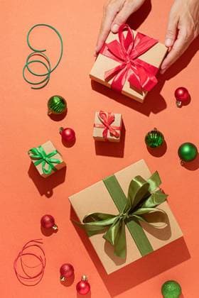 A vibrant arrangement of Christmas gifts tied with colorful ribbons alongside glittering baubles, captured on a lively orange backdrop The scene exudes the holiday spirit with a focus on gift-giving and seasonal decor Model Released OlgaVila_ID24323_705079_005 Copyright: xOlgaxVilax