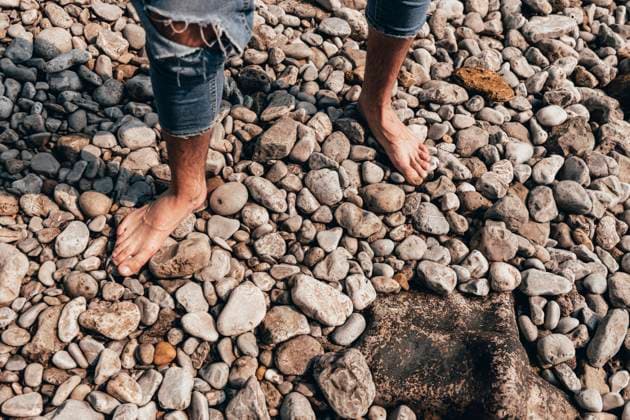 Creative Highlights Symbolfotos A close-up view of a man s bare feet as he walks across a pebble-covered beach in Santander, Spain His jeans are casually rolled up, highlighting the natural texture of the rounded stones Model Released PaulaBerezo_ID24306_704429_003 Copyright: xPaulaxBerezox