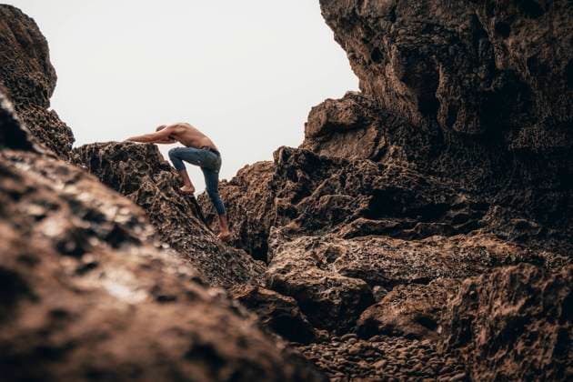 Creative Highlights Symbolfotos A shirtless man climbs a rugged, rocky shoreline in Santander, Spain, showcasing strength and agility against a textured natural background Model Released PaulaBerezo_ID24306_704444_004 Copyright: xPaulaxBerezox