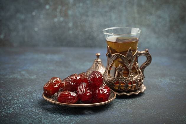 Fastenbrechen mit getrockneten Datteln während des Ramadan Kareem, Iftar Mahlzeit mit Datteln und arabischem Tee im traditionellen Glas, Blickwinkel auf rustikalem blauen Hintergrund. Muslimisches Festmahl, Foodfotografie Breaking fasting with dried dates during Ramadan Kareem, Iftar meal with dates and Arab tea in traditional glass, angle view on rustic blue background. Muslim feast, food photography, food photography Copyright: imageBROKER OlenaxYeromenko ibxiqx11318000.jpg