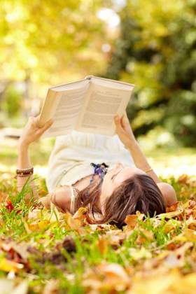 Reading, book and woman relax in park with novel in nature learning for education as student outdoor on campus. University, college and young person with textbook on grass field for scholarship. model released property released Copyright: xwww.peopleimages.comx