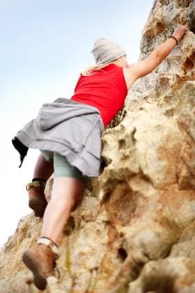 Woman on cliff, rock climbing and hiking adventure in mountain with nature, freedom and power. Travel, girl trekking and hanging, strong person in countryside on natural outdoor journey with fitness model released property released Copyright: xwww.peopleimages.comx