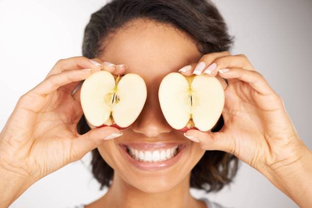 IMAGO Creative, Naturkosmetik Happy woman, apple and eyes for diet, nutrition or health and wellness against a gray studio background. Portrait of female person or nutritionist smile with organic fruit slices for vitamin or fiber. model released property released Copyright: xwww.peopleimages.comx