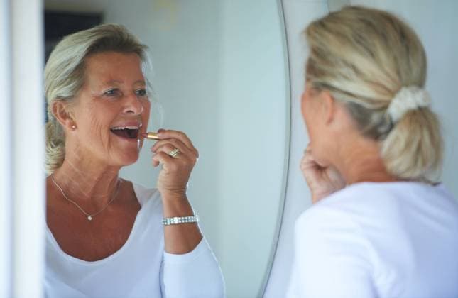 IMAGO Creative, Naturkosmetik Senior woman, lipstick and mirror in home with smile, thinking and beauty to start morning in retirement. Elderly person, makeup and product for lips, reflection and happy in bathroom for cosmetics. model released property released Copyright: xwww.peopleimages.comx