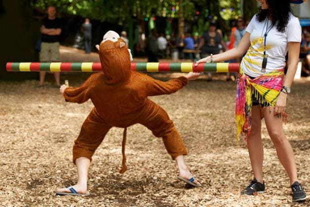 Summer, vacation and man in game of limbo, balance and playing at a music festival, event and challenge. Fun, people and outdoor in woods, forest or person in social activity at party in monkey suit. model released property released Copyright: xwww.peopleimages.comx
