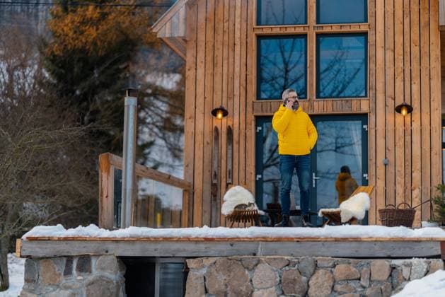 Man working from cozy cabin in mountains, making call with client. Concept of remote work from beautiful, peaceful location. Hygge at work. Man working from cozy cabin in mountains, making call with client. Concept of remote work from beautiful, peaceful location. model released