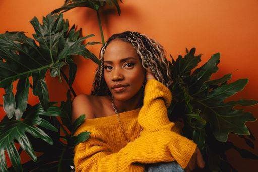 Creative Highlights Symbolfotos A portrait of an african female model with braided hair and yellow sweater on an orange background 25380351 ,model released, Symbolfoto RECORD DATE NOT STATED