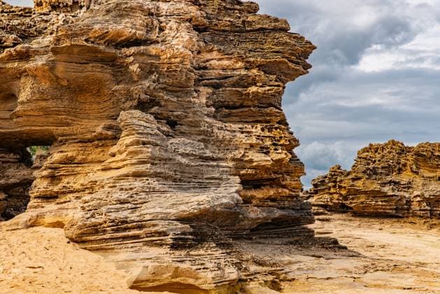 Creative Highlights World Rugged rock formation under a stormy sky along a sandy coastal area Point Lonsdale, Victoria, Australia CR_FABX241011-1558315-01