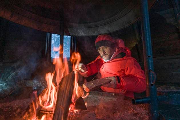Hiker man warms up at fireplace in a mountain hut, Lapland, Finland Kittilä, Lapland, Finland CR_ROMO2407090F-1472562-01 ,model released, Symbolfoto