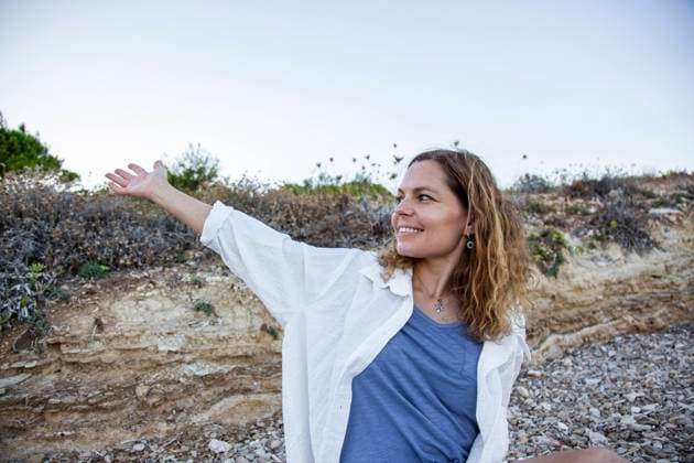 Creative Highlights Symbolfotos Beautiful woman on a rocky beach smiling and extending her arm outward Çe?me, ?zmir, Türkiye R_THNZ241015B-1560718-01 ,model released, Symbolfoto
