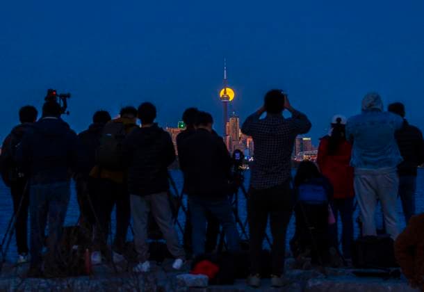 (241018) -- TORONTO, Oct. 18, 2024 -- People film the full moon rising over the skyline in Toronto, Canada, on Oct. 17, 2024. (Photo by Xinhua) CANADA-TORONTO-FULL MOON ZouxZheng 