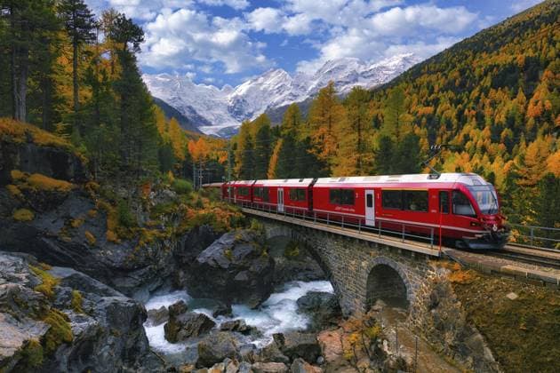 Rhätische Bahn RhB überquert ein Bergbach über eine Steinbrücke, dahinter herbstfarbenes Val Morteratsch mit schneebedeckten Bergen, Engadin, Kanton Graubünden, Schweiz, Europa Rhaetian Railway RhB crossing a mountain stream over a stone bridge, behind it autumn-coloured Val Morteratsch with snow-covered mountains, Engadine, Canton Grisons, Switzerland, Europe Copyright: imageBROKER DanielxBärtschi ibxdab11587800.jpg