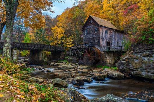 An old wooden mill by a stream in autumn, surrounded by colorful foliage. Babcock State Park, WV 26303555 RECORD DATE NOT STATED