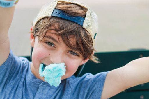 Creative Highlights Symbolfotos A boy with a cap enjoying blue cotton candy outdoors, smiling on a sunny day in Orlando, Florida 26359240 ,model released, Symbolfoto RECORD DATE NOT STATED