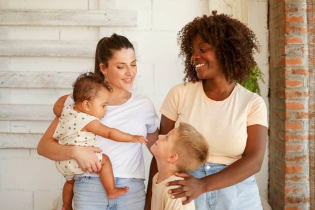 A multiracial lesbian family shares a joyful moment together. The Caucasian and African American mothers are smiling and interacting with their children. The boy is looking up at his mother, while the toddler interacts with him Model Released HaruUraraStudio_ID24143_699789_047 Copyright: xHaruxUraraxStudiox RECORD DATE NOT STATED