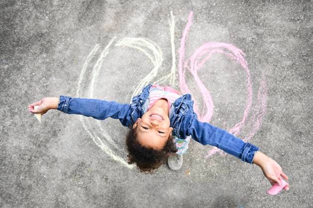 Creative Highlights Symbolfotos Smiling child holding chalk, arms outstretched, drawing on pavem United States, Florida, Inverness CR_YWQX241022-1567286-01 ,model released, Symbolfoto