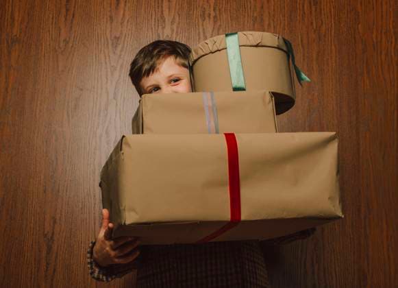 Happy boy carrying Christmas presents in front of wooden wall model released, Symbolfoto, VSNF02527