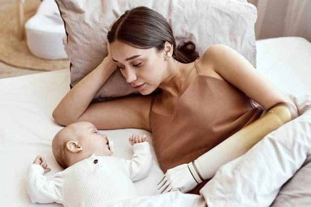 IMAGO Creative, Diversity, Mütter Young woman with amputated arm lying beside sleeping baby boy on bed at home model released, Symbolfoto property released, KPEF00851