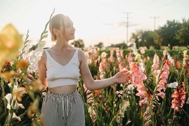 Smiling woman touching gladiolus flowers in field on sunny day model released, Symbolfoto, MCHF00261
