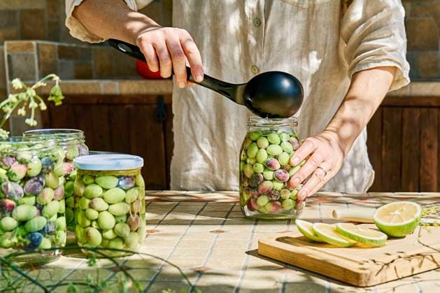 Mature woman preparing fermented olives in glass jar model released, Symbolfoto property released, CATF00449