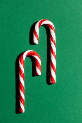 Top view of two intertwined red and white striped candy canes positioned on a vibrant green background, highlighting a classic Christmas treat. Model Released AlexSalcedo_ID24525_711085_006 Copyright: xAlexxSalcedox RECORD DATE NOT STATED