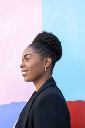 Creative Highlights Symbolfotos Side view of a smiling African American woman looking away, set against a colorful blue and pink background. She appears confident and stylish in her black outfit. Model Released DavidMunoz_ID24206_701852_036 Copyright: xDavidxMunozx