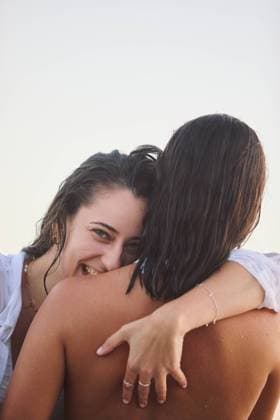 Creative Highlights Symbolfotos Two lesbian women share a loving embrace at Playa de Nerga, Galicia. One woman smiles joyfully at the camera while hugging the other from behind, capturing a moment of genuine affection and connection. Model Released FranciscoDapenaDuran_ID24024_696711_045 Copyright: xFranciscoxDapenaxDuranx RECORD DATE NOT STATED