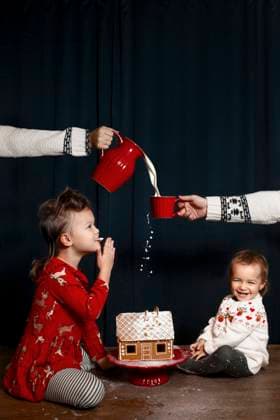 Creative Highlights Symbolfotos Two little children enjoy Christmas cheer and delight in a gingerbread house while adults pour milk into a red cup A cozy and festive atmosphere enhances the feeling of Christmas celebration Model Released KateSurzhok_ID24536_711316_001 Copyright: xKatexSurzhokx RECORD DATE NOT STATED
