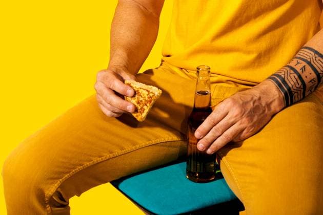 A vibrant scene featuring a man dressed in a yellow suit, holding a piece of Spanish tortilla and a bottle of beer, against a monochrome yellow background Model Released SergioVictorVega_ID24526_711158_021 Copyright: xSergioxVictorxVegax RECORD DATE NOT STATED
