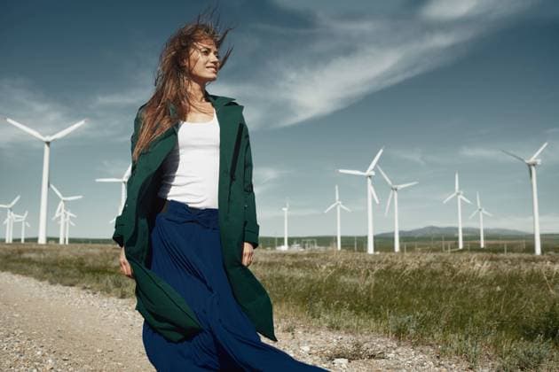 Creative Highlights Symbolfotos A serene image depicting a woman in a vibrant ensemble standing confidently near a field of majestic wind turbines, symbolizing a harmony between human and renewable energy use Model Released Zhenikeyev_ID15391_468806_017 Copyright: xx RECORD DATE NOT STATED
