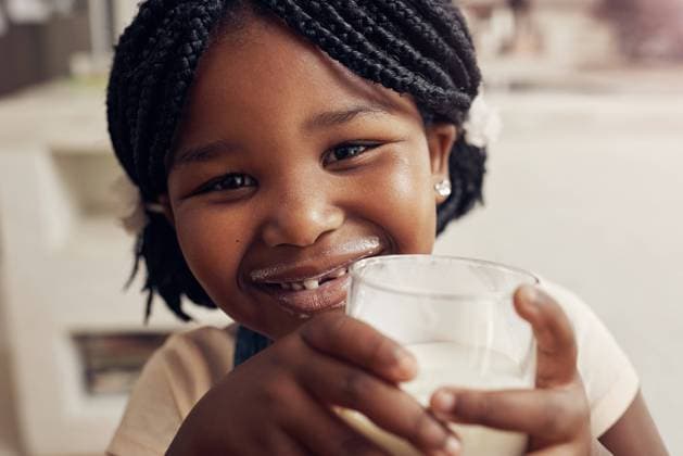 Black girl, drink milk and portrait in home for nutrition, hygiene and dental health in kitchen. Family house, child and glass of dairy product for wellness, protein and vitamins for growth for kid. model released property released Copyright: xwww.peopleimages.comx
