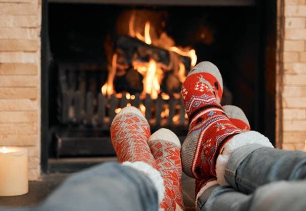 Couple, Christmas and socks by fireplace for celebration to relax at house, romantic and bonding on holiday in winter. People, legs and warm for home, together and love for comfort, wool and heat. model released property released Copyright: xwww.peopleimages.comx