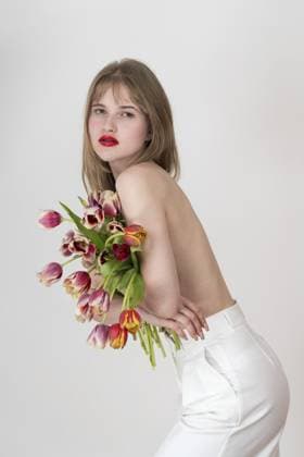Porträt einer ernsten Frau, die einen Strauß Tulpenblüten umklammert und ihre Brust mit Blumen bedeckt und in die Kamera schaut. Schöne junge blonde kaukasische Frau stehend beugt sich über weißen Hintergrund Portrait of serious woman clutching bouquet of spring tulip flowers and covering chest with flowers and looking at camera. Beautiful young blonde Caucasian woman standing bending over white background Copyright: imageBROKER AlexanderxA.xPiragis ibxiqx11670579.jpg ,model released, Symbolfoto ,property released