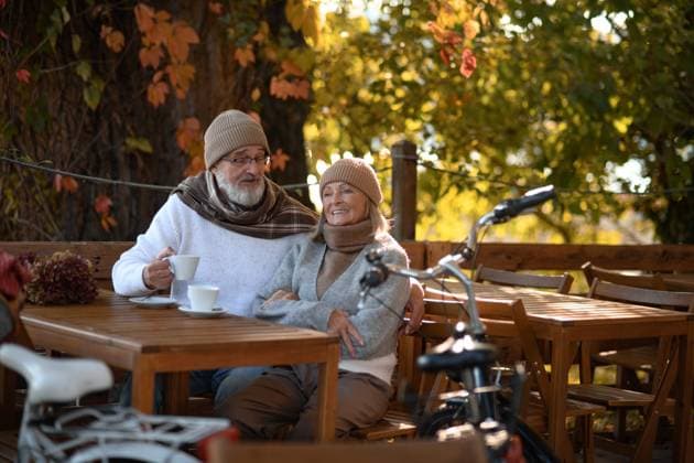 Elderly married couple sitting on a coffee shop terrace on beautiful autumn day, enjoying cup of coffee in the autumn atmosphere. Elderly married couple sitting on a coffee shop terrace on beautiful autumn day, enjoying cup of coffee in autumn atmosphere. model released