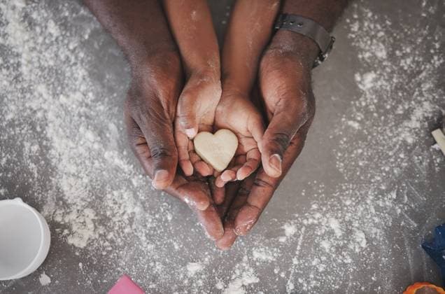 Hands, family and kid baking with heart cookie, father and love in kitchen with learning and flour. Home, dough above and cooking with teaching, youth development and support together with dessert. model released property released Copyright: xwww.peopleimages.comx