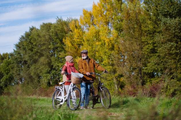 IMAGO Creative, Jahreszeit Herbst auf dem Land Elderly couple on a walk in the forest, pushing their bikes side by side. Seniors in love on stroll through autumn nature, enjoying a peaceful moment together. Elderly couple on walk in the forest, pushing their bikes side by side. Seniors in love on stroll through autumn nature, enjoying a peaceful moment together. model released