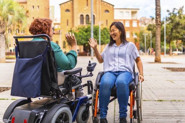 Zwei multiethnische Frauen mit Behinderungen in Rollstühlen verabschieden sich auf der Straße Two multi-ethnic women with disabilities in wheelchairs saying goodbye on the street Copyright: imageBROKER UnaixHuizi ibxuhu11724694.jpg ,model released, Symbolfoto ,property released