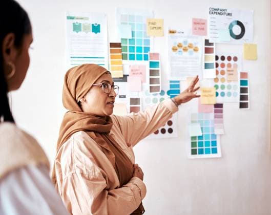 Planning, teamwork and presentation with a business muslim woman talking to her team in the office. Creative, strategy and collaboration with a female manager teaching or coaching an employee group. model released property released Copyright: xwww.peopleimages.comx