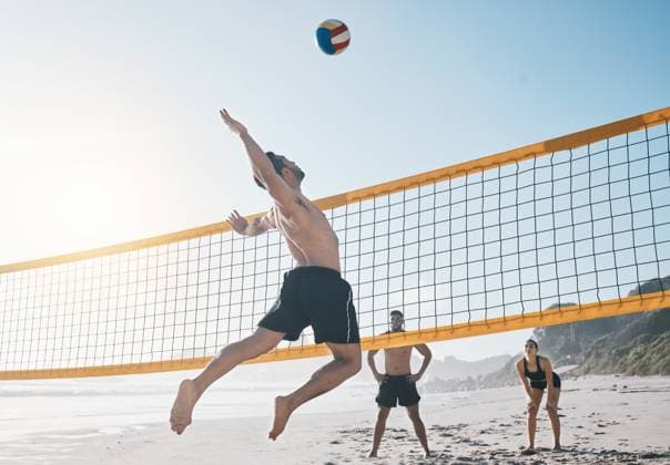 Man, jump and volleyball in air on beach by net in sports match, game or competition. Body of male person jumping for ball in volley or spike in healthy fitness, energy or exercise by the ocean coast. model released property released Copyright: xwww.peopleimages.comx